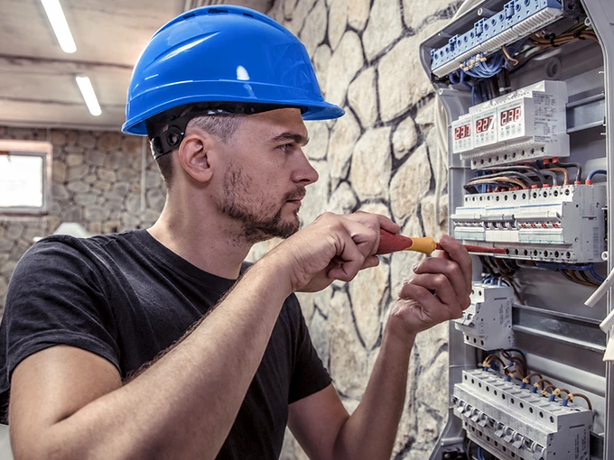 Worker using an electrical tester to inspect a fuse